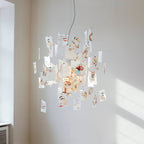 Cards printed with painted faces hang from this Clérachic paper pendant in a pale room with sunlight on the wall.