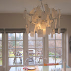 In front of tall glazed doors, a Clérachic paper pendant is full of handwritten notes, glowing warm above a laid table.