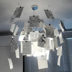 Black ink sketches of figures cover the cards on this Clérachic paper pendant, seen from below against blinds and a ceiling.