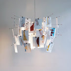 Abstract line drawings in red, tan and blue decorate the cards of this Clérachic paper pendant, seen from the side.
