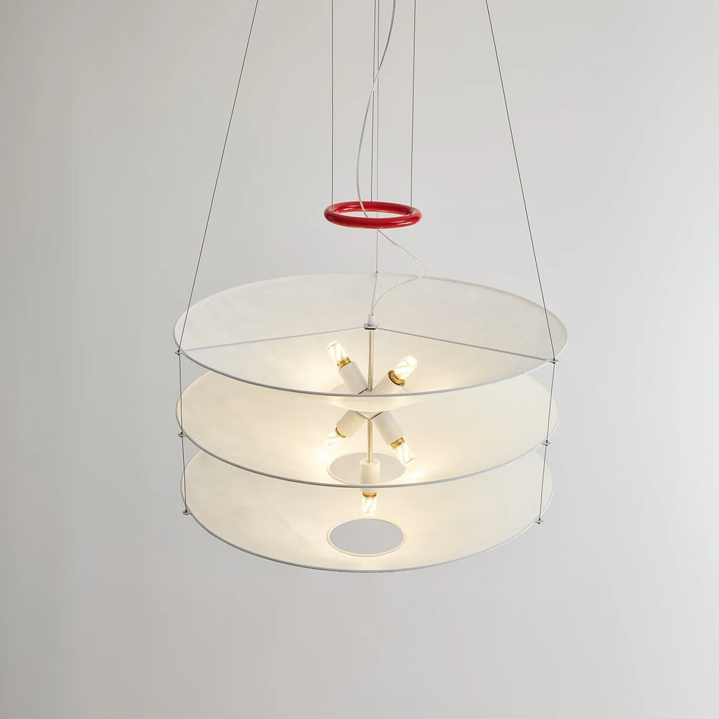 Seen from the side against a plain wall, the three paper tiers of this Clérachic pendant show small bulbs lit inside, with a red ring on the cables.