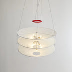 Seen from the side against a plain wall, the three paper tiers of this Clérachic pendant show small bulbs lit inside, with a red ring on the cables.