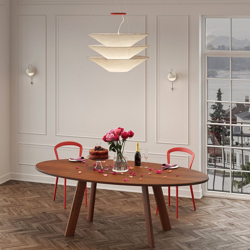 Above an oval timber table set for a celebration with roses, this Clérachic paper pendant hangs in a panelled room by a tall window.