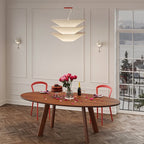 Above an oval timber table set for a celebration with roses, this Clérachic paper pendant hangs in a panelled room by a tall window.