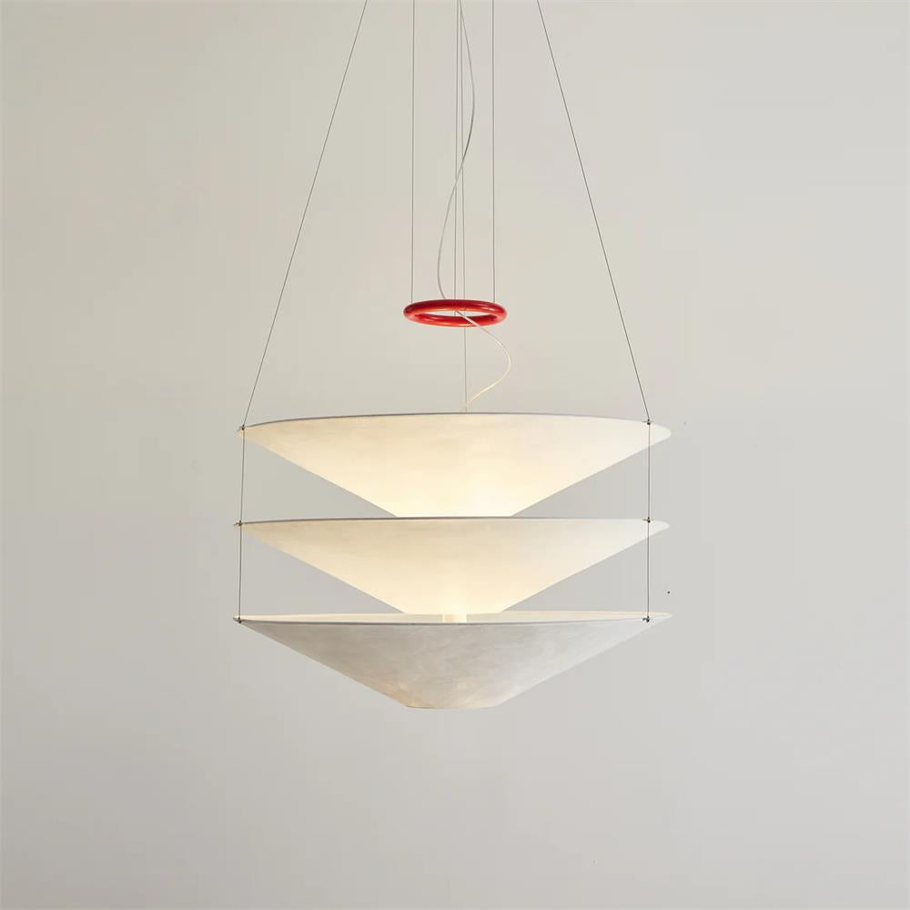 This Clérachic pendant has three widely spaced paper cones joined by fine cables, shown glowing against a plain pale wall.