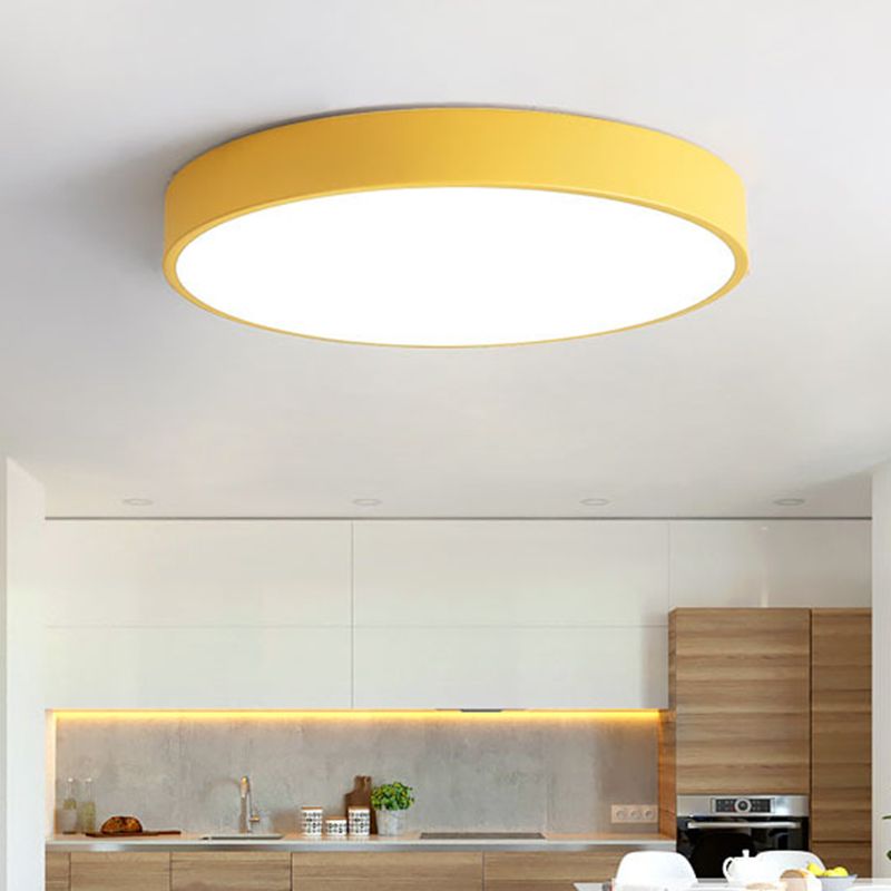 A mustard-yellow Clérachic flush mount ceiling light glows above a wood and white kitchen counter.
