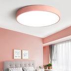 This blush-pink Clérachic flush mount ceiling light brightens a rosy bedroom with a tufted grey headboard.