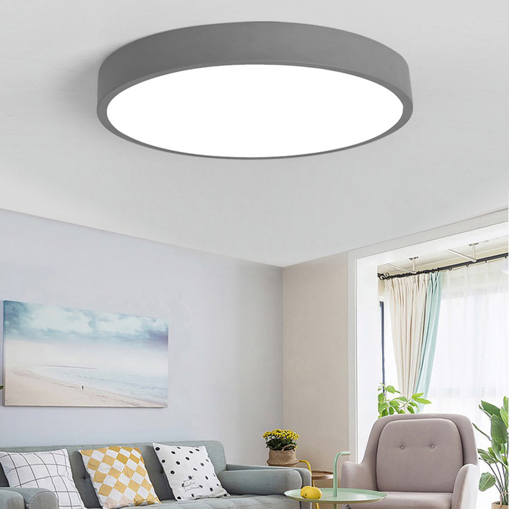 A warm-grey Clérachic flush mount ceiling light is shown at an angle, lighting a cozy living room seating area.