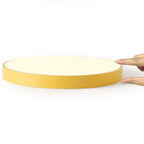 Edge-on view of a mustard-yellow Clérachic flush mount ceiling light held between two fingers, showing its slim profile.