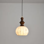 Clérachic pendant lamp lit above an empty grey wall, the vertical folds of the shade reading as soft bands of light.