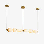 Six alabaster pebbles in a row on this Clérachic linear chandelier, hung from three gold canopies on a plain white background.