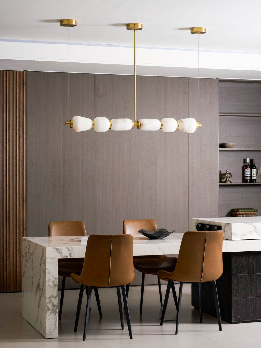 Clérachic alabaster chandelier hanging above a marble dining table with tan leather chairs, against walls of grey-brown timber.