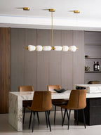 Clérachic alabaster chandelier hanging above a marble dining table with tan leather chairs, against walls of grey-brown timber.