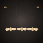 Clérachic gallery view of nine flat, rough-hewn stone pebbles strung in a long row below gold canopies, against a near-black background.