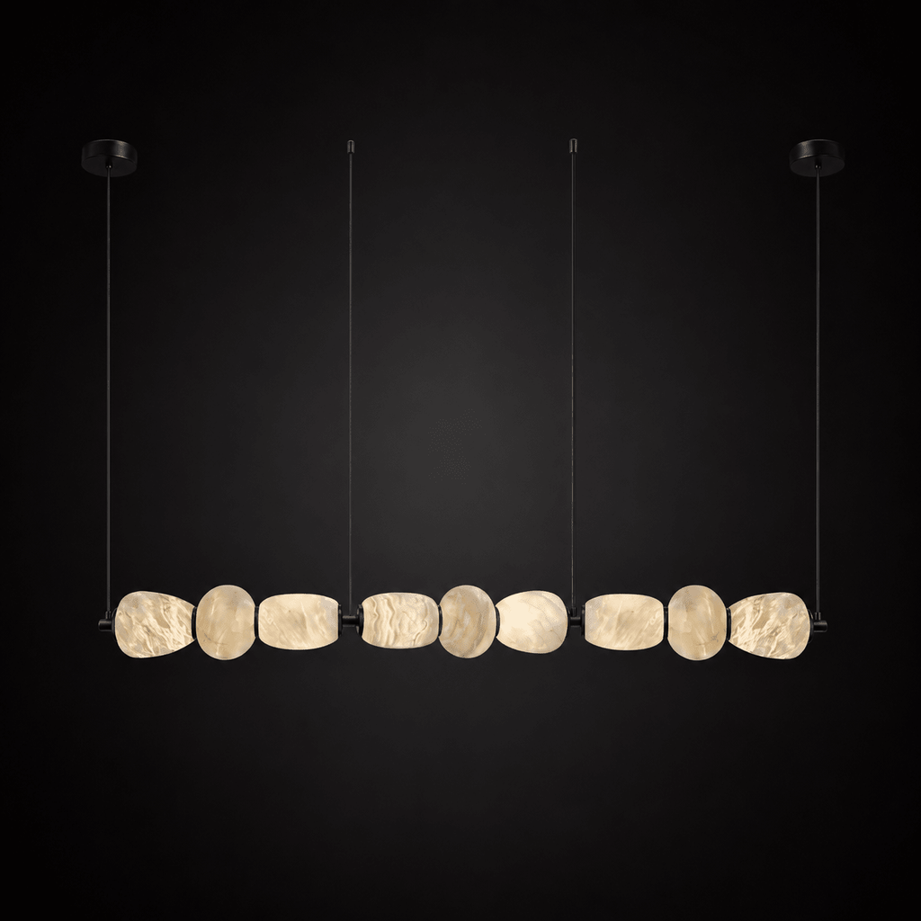 Clérachic gallery view of a row of nine flat stone pebbles with black fittings hanging against a dark backdrop, lit softly from within.