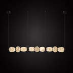 Clérachic gallery view of a row of nine flat stone pebbles with black fittings hanging against a dark backdrop, lit softly from within.