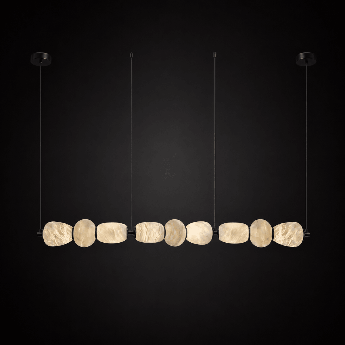 Clérachic gallery view of a row of nine flat stone pebbles with black fittings hanging against a dark backdrop, lit softly from within.