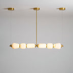 Gold-fitted Clérachic chandelier with six lit alabaster pebbles, shown from a low angle against a pale grey ceiling and wall.