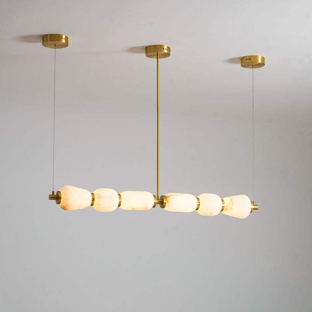 From a lower angle, the lit pebbles of this Clérachic linear chandelier glow warm white under its gold ceiling canopies.