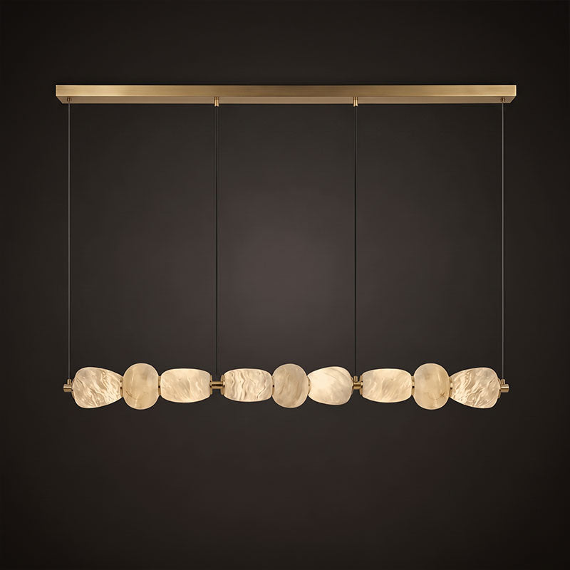Clérachic gallery view of a long gold canopy bar over a row of nine flat stone pebbles lit softly, hanging against a dark brown backdrop.