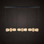 Clérachic gallery view of a long black canopy bar over a row of nine flat stone pebbles with a warm glow, against a dark backdrop.