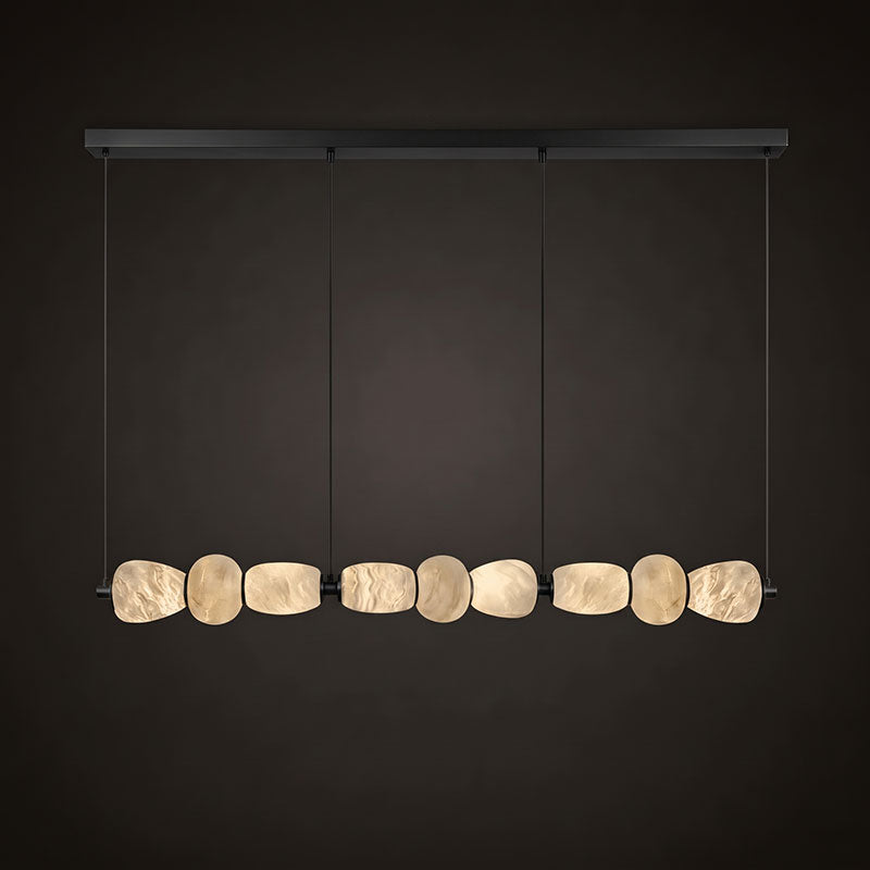 Clérachic gallery view of a long black canopy bar over a row of nine flat stone pebbles with a warm glow, against a dark backdrop.