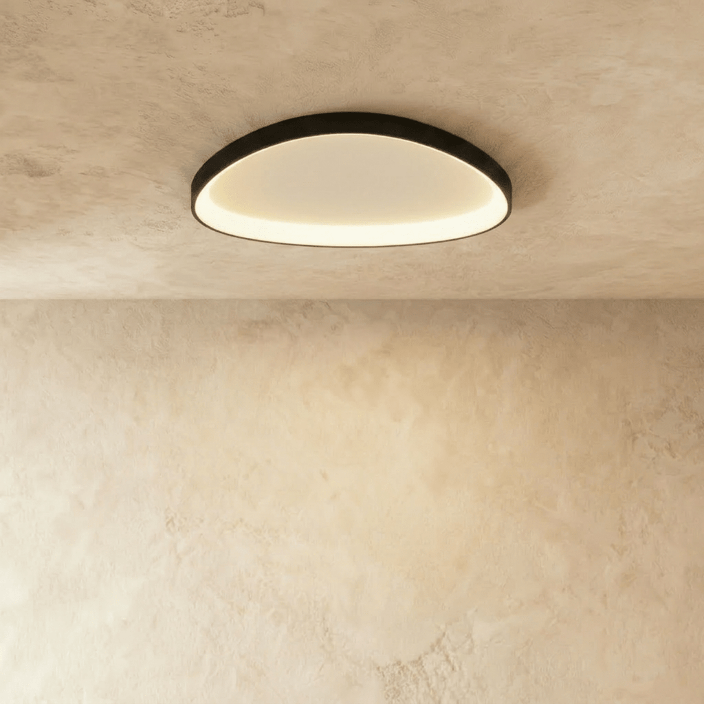 Clérachic larger black aluminium ceiling light with a luminous inner edge, mounted flush on a pale plaster ceiling.