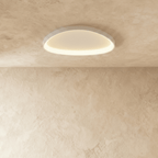 Clérachic white aluminium ceiling light with a soft oval outline, its inner rim glowing warm on a plaster ceiling.