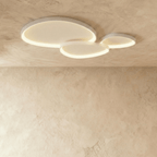 Clérachic group of three white pebble-shaped ceiling lights overlapping, glowing warm on a textured plaster ceiling.