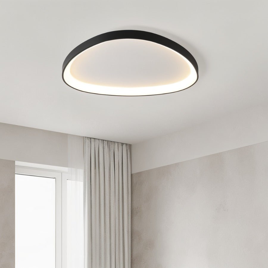Clérachic single black oval ceiling light glowing warm in a bedroom with a sheer curtain and a bright window.
