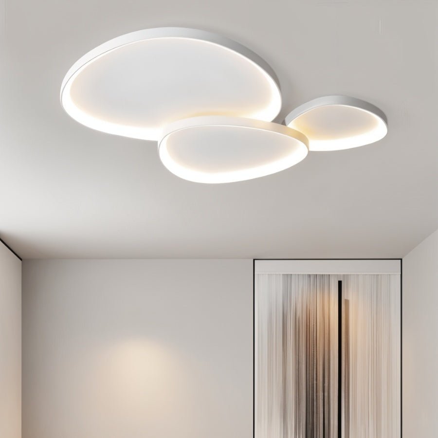 Clérachic cluster of three white ceiling lights lit warm in a hallway with a fringed curtain panel on the far wall.