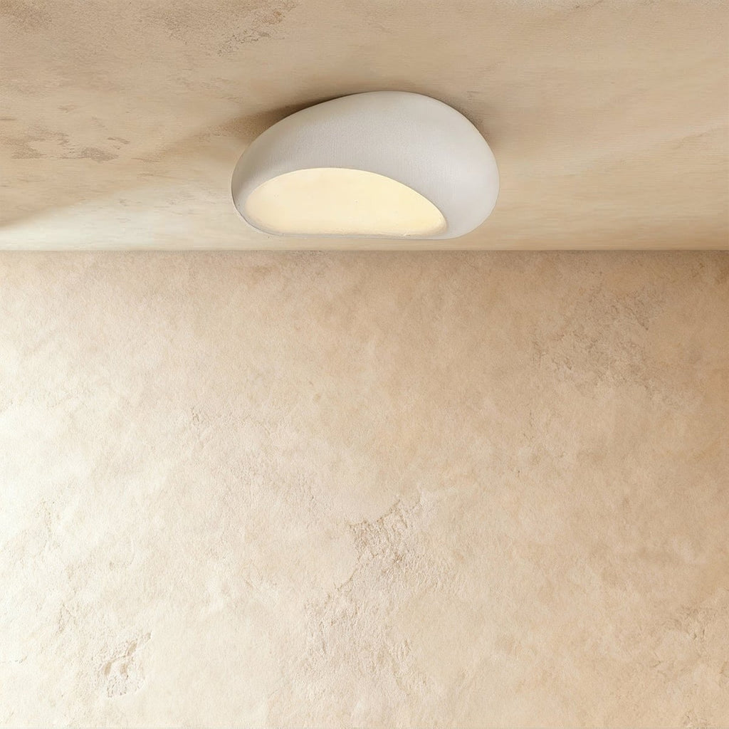 Clérachic small matte white pebble flush ceiling light with a soft textured shell and a warm glow underneath.