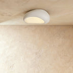 Clérachic small matte white pebble flush ceiling light with a soft textured shell and a warm glow underneath.