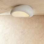Clérachic large white pebble flush ceiling light with a smooth textured shell and a soft lit opening.