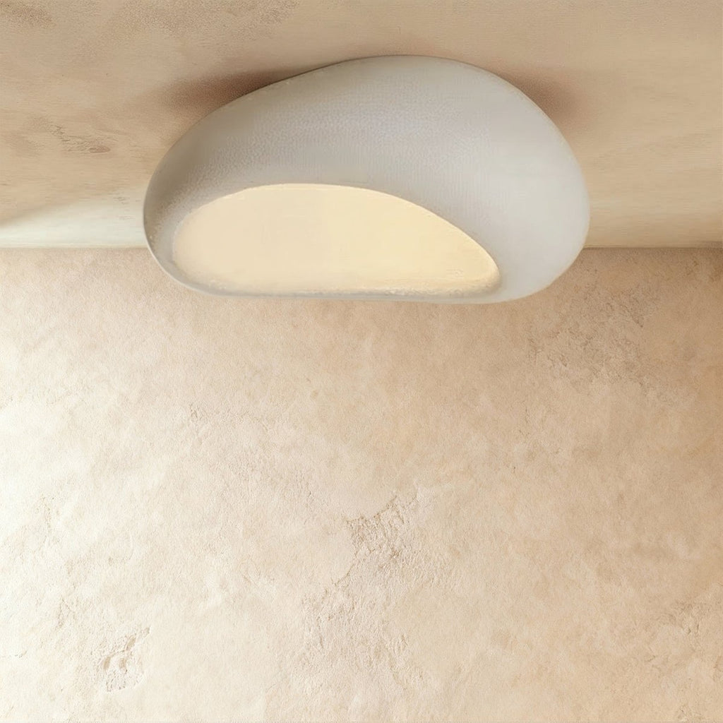 Clérachic extra-large white pebble ceiling light with a wide frosted opening, glowing warm on a plaster ceiling.