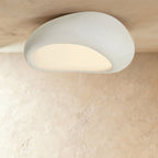Clérachic largest white pebble flush ceiling light, its broad curved shell and warm lit opening filling the frame.