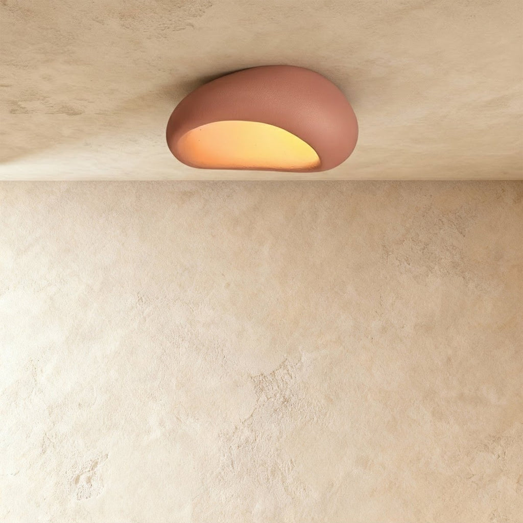 Clérachic terracotta pink pebble ceiling light, slightly larger, with a matte textured shell and an amber glow.