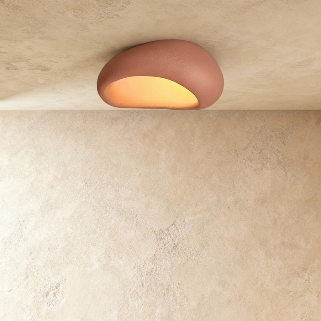 Clérachic pink pebble-shaped flush ceiling light with a matte shell, lit warm from the underside.