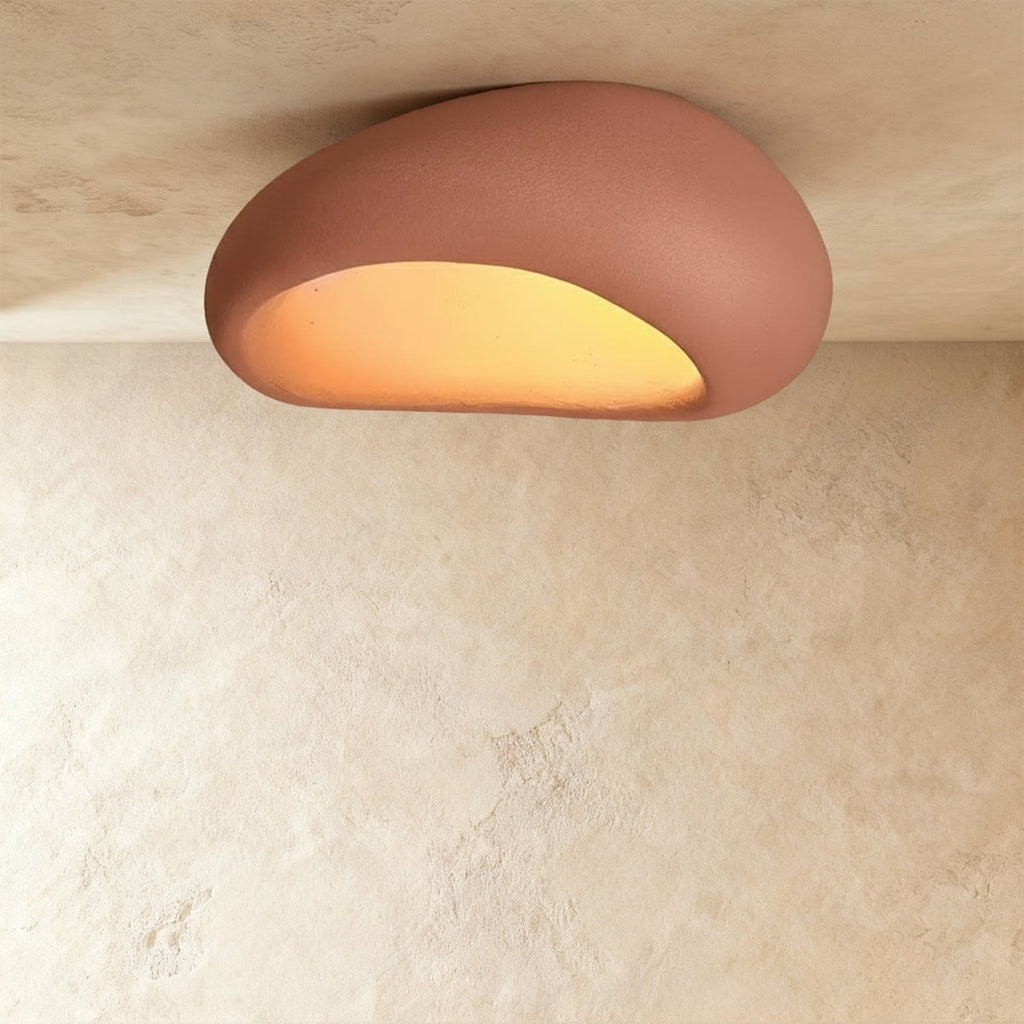 Clérachic big terracotta pink pebble ceiling light with a matte textured shell and a glowing amber opening.