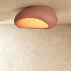 Clérachic big terracotta pink pebble ceiling light with a matte textured shell and a glowing amber opening.