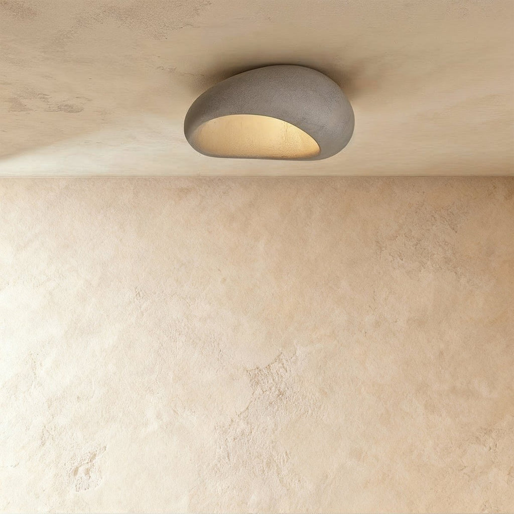 Clérachic small grey pebble-shaped flush ceiling light with a mottled matte shell and a warm glow beneath.