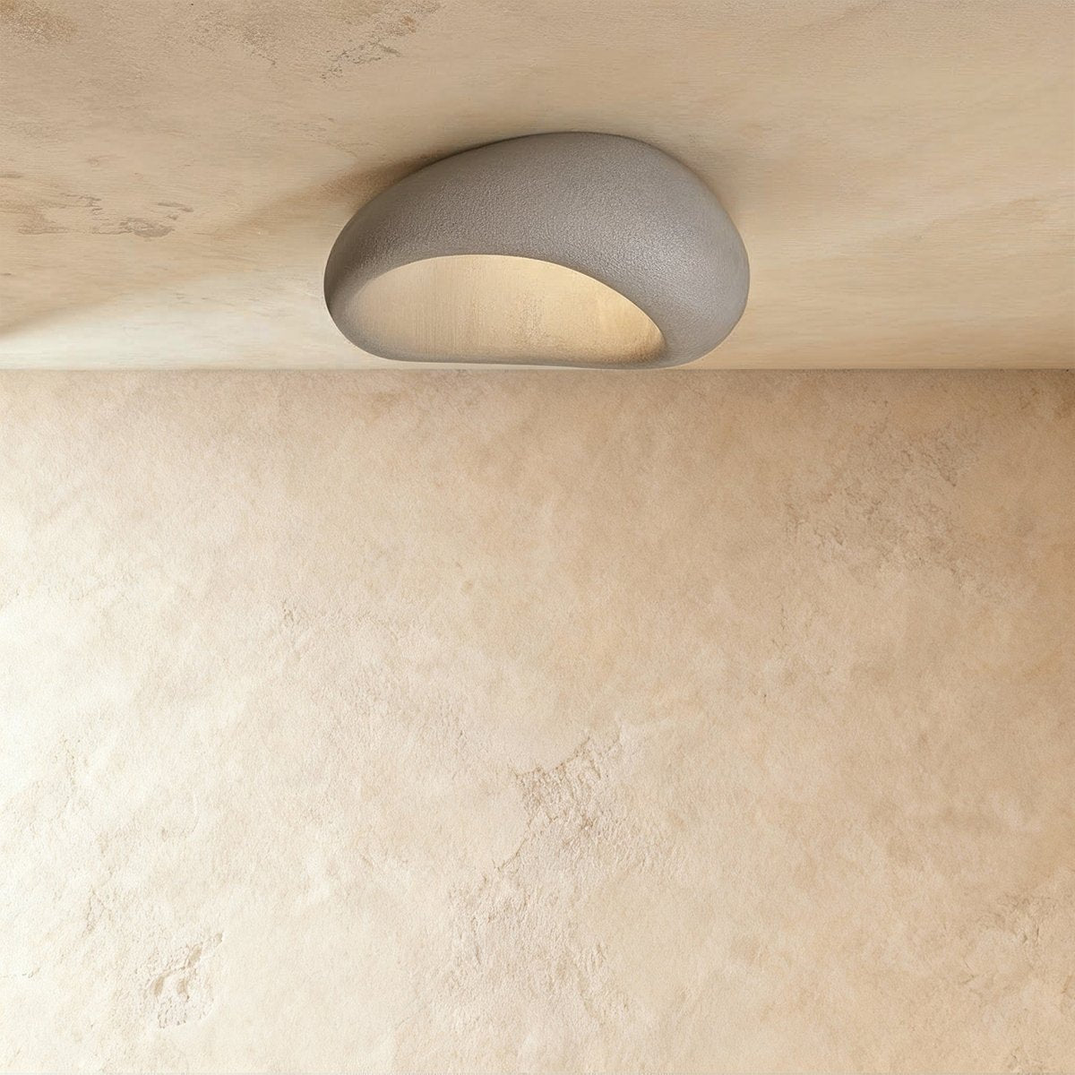 Clérachic grey pebble ceiling light with a rough textured shell and a softly lit curved opening.