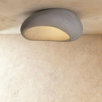 Clérachic large grey pebble flush ceiling light with a smooth shell and a warm cream glow inside the opening.