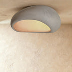 Clérachic extra-large grey pebble ceiling light with a broad matte shell and a glowing opening, close to the ceiling.