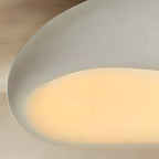 Close view of a Clérachic white pebble ceiling light, showing the fine textured shell and the warm frosted opening.