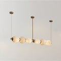Clérachic Pebble chandelier on white, a row of alabaster forms threaded along a slim brass rod.