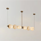 Clérachic Pebble chandelier on white, a row of alabaster forms threaded along a slim brass rod.