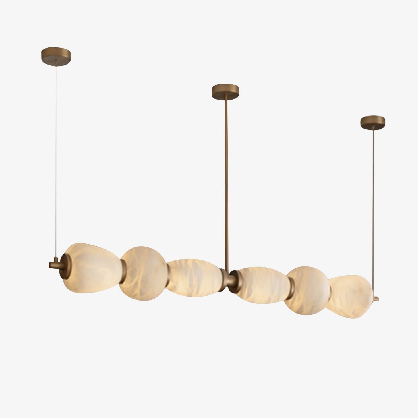 The Clérachic Pebble linear chandelier lit on white, stone shapes graduating along the bar.