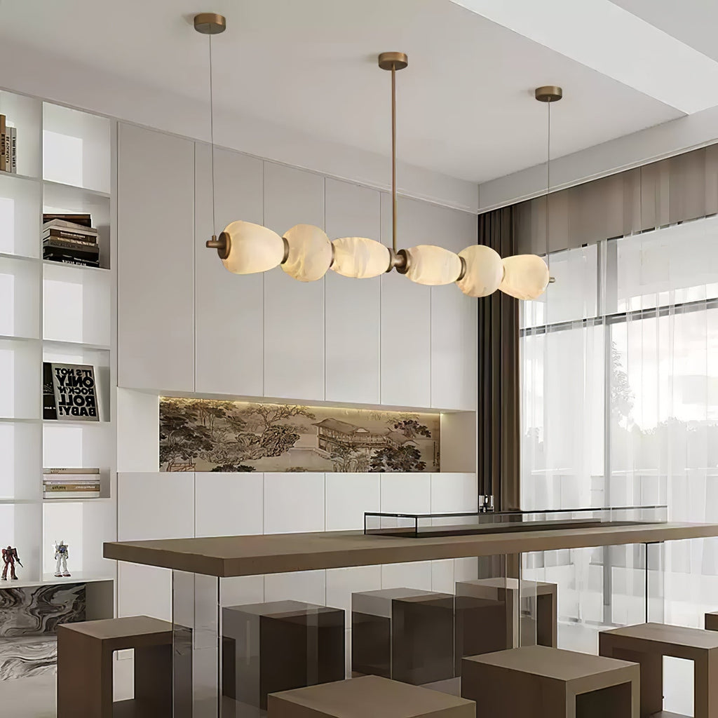 Clérachic Pebble chandelier over a long dining bar in a bright open-plan living space.