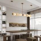Clérachic Pebble chandelier over a long dining bar in a bright open-plan living space.